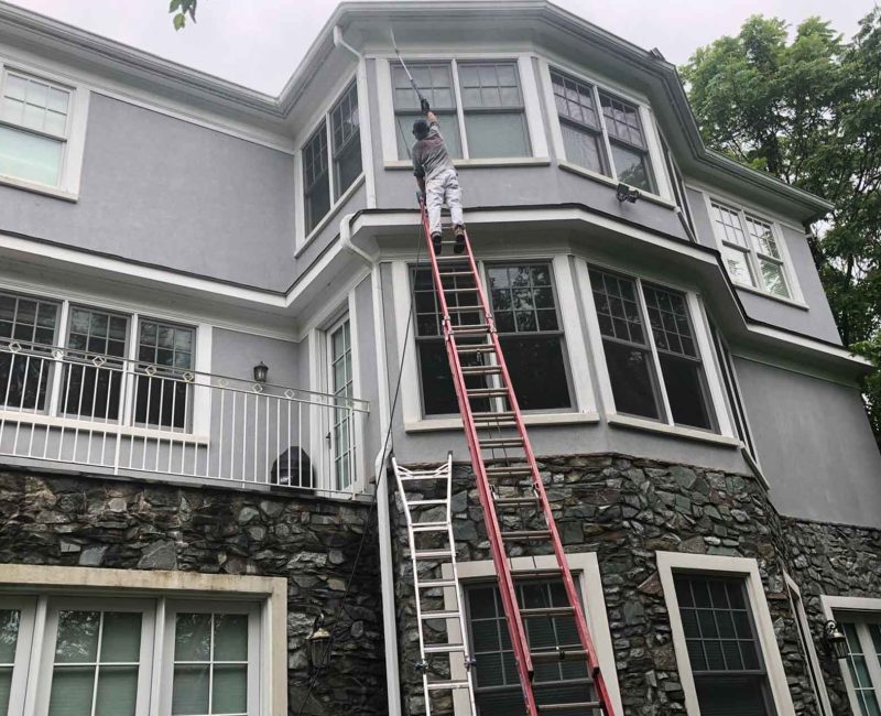 4 Worker on ladder painting exterior of a gray modern house.