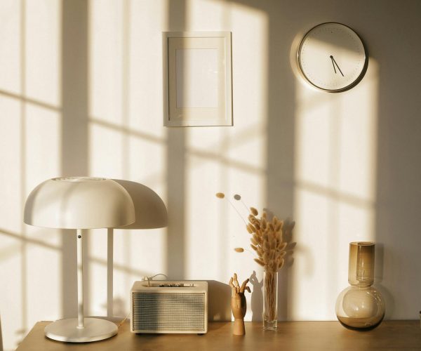 Minimalist home decor with lamp, radio, and clock in sunlit room.