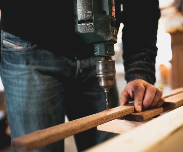 pexels-thijsvdw-1094767 Craftsman drilling into wood in a workshop setting.